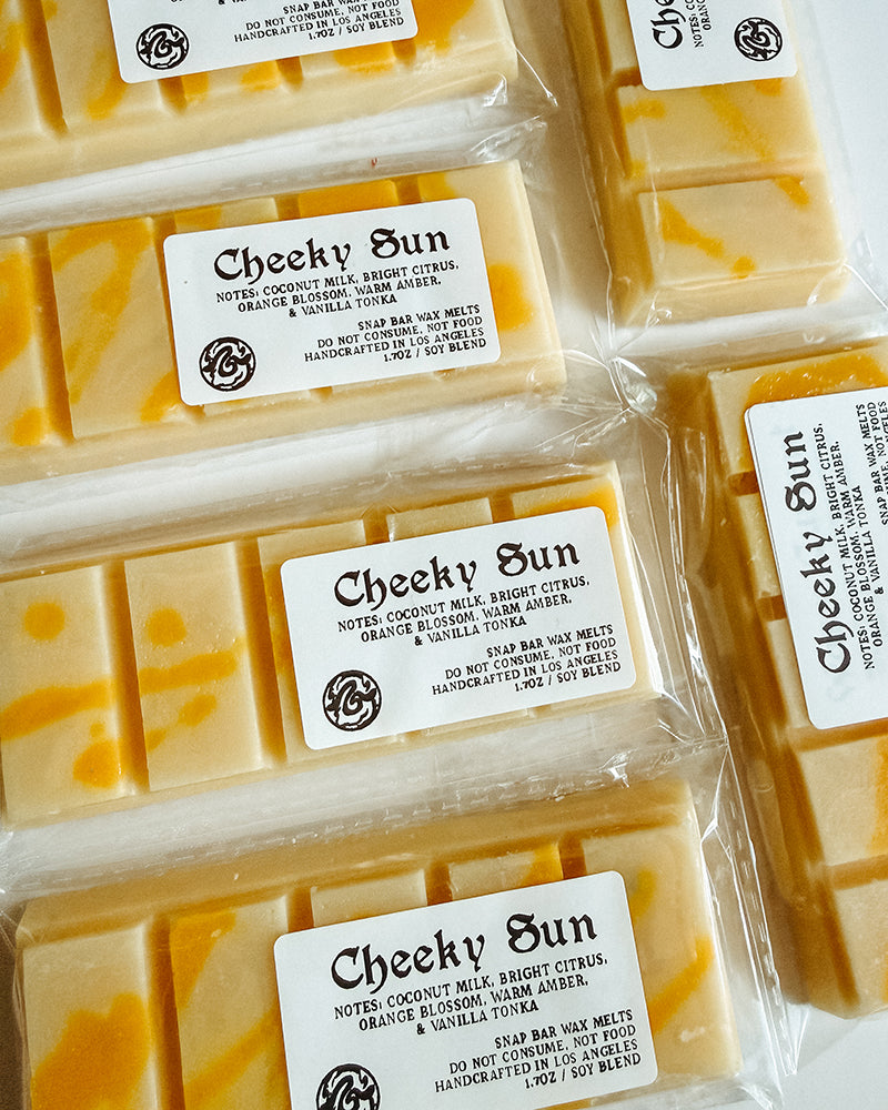 Packaged wax bars with 'Cheeky Sun' labels on a white background