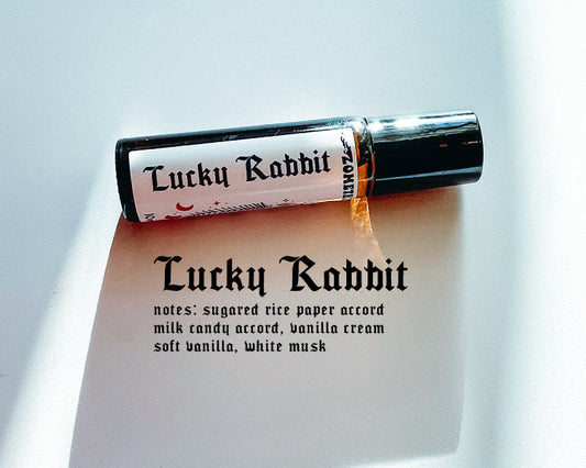 Roll-on bottle of Lucky Rabbit perfume with a description card on a light background