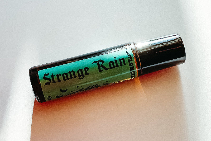 Roll-on bottle labeled 'Strange Rain' on a light background